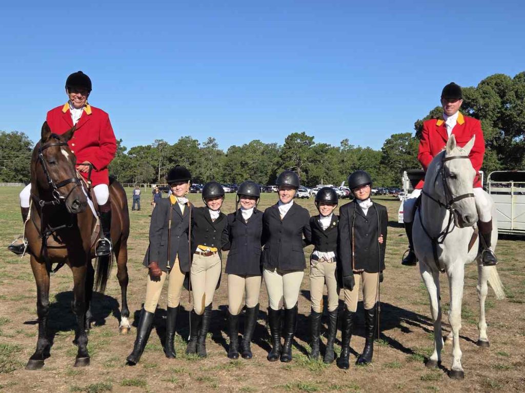 Group of juniors standing between two mounted huntsmen